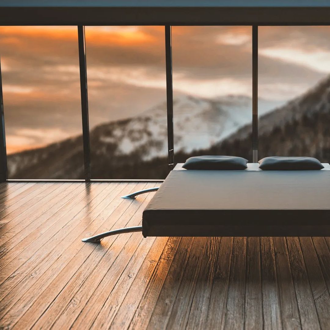 a mountain-view room with a simple black bed and bright, lustrous hardwood floors