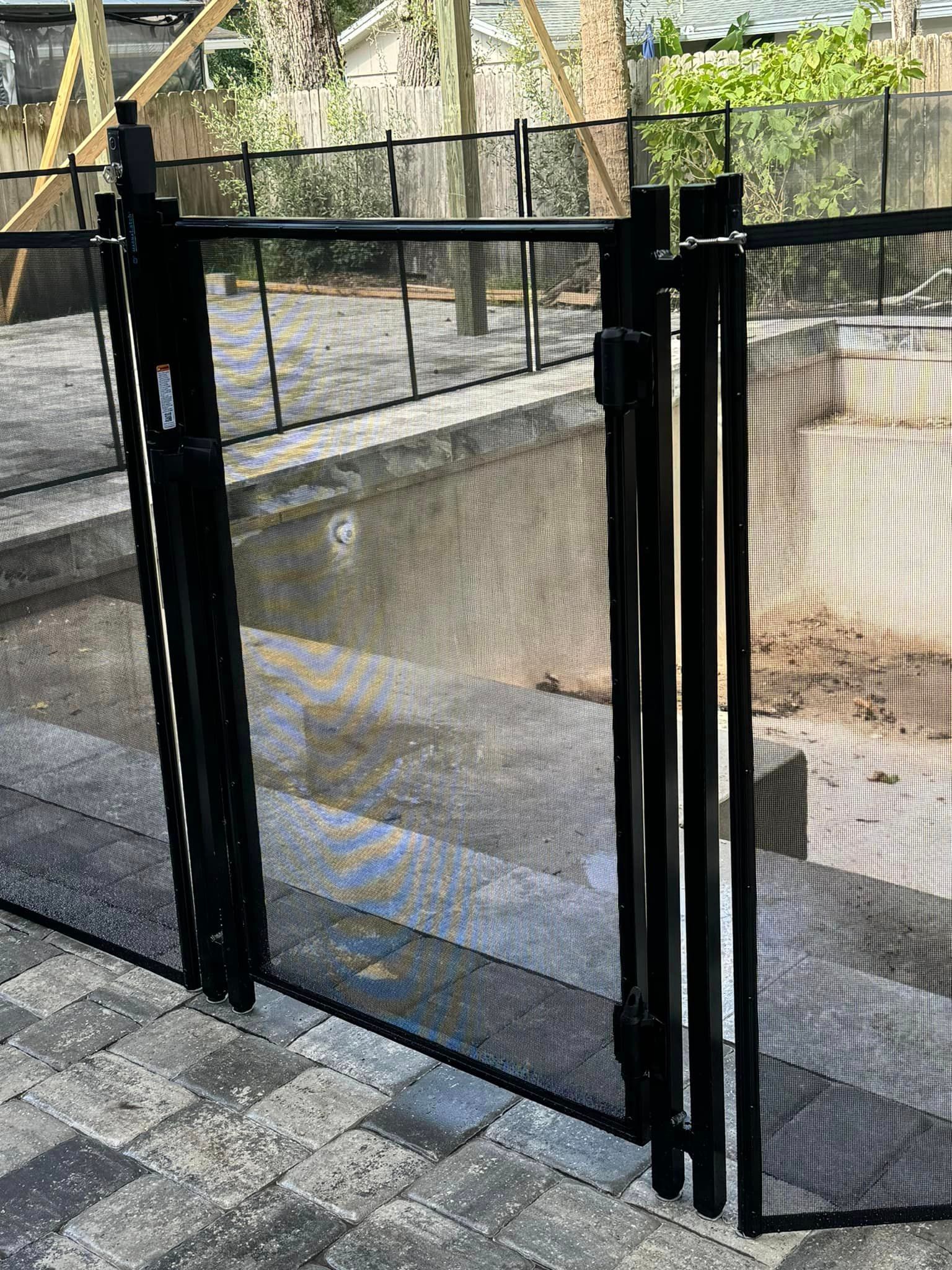 A black gate is sitting next to a swimming pool.