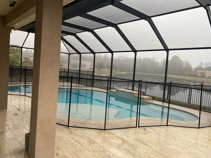 A screened in swimming pool with a fence around it.