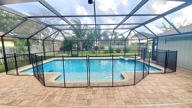 A large swimming pool with a screened in area and a fence around it.