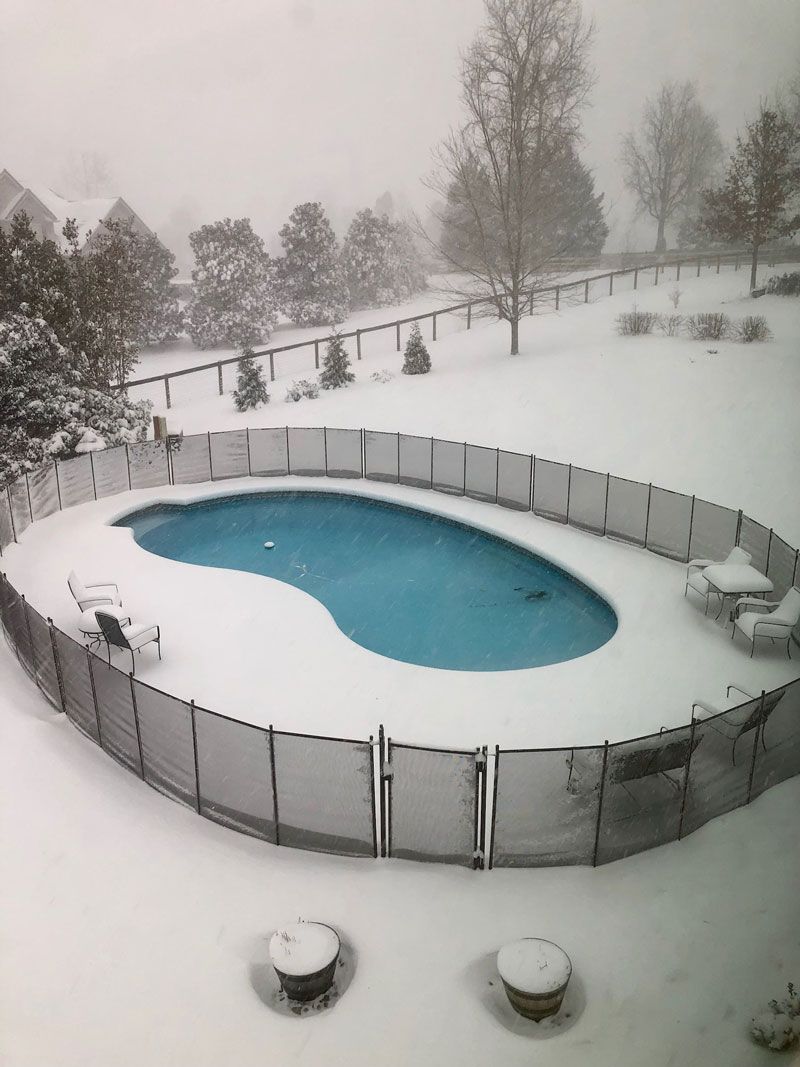 A swimming pool surrounded by a snow covered fence
