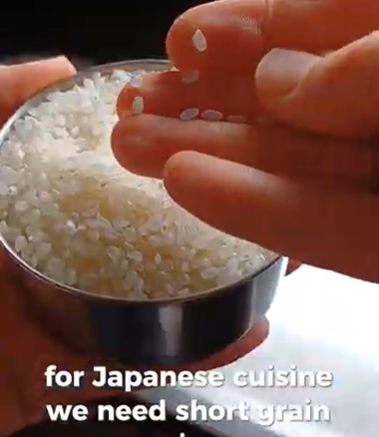 A hand holding short-grain rice over a small metal bowl, with text stating it is required for Japanese cuisine.