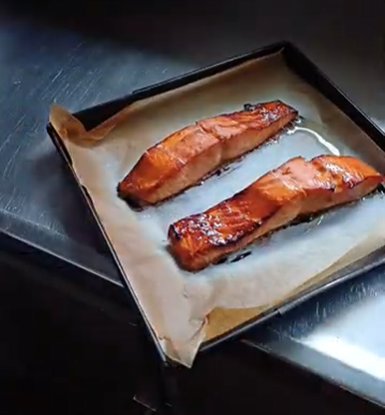 Two cooked salmon fillets on a baking sheet lined with parchment paper.