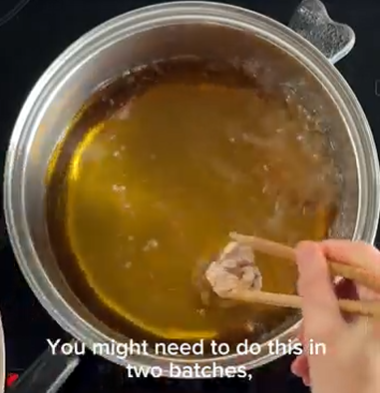 Hand holding a spoon over a pot of brown broth, with subtitle text at the bottom.
