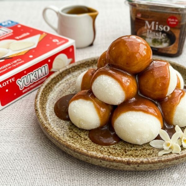 Eight white round Yukimi Vanilla served on a light plate, generously covered in a thick, dark brown miso caramel glaze.