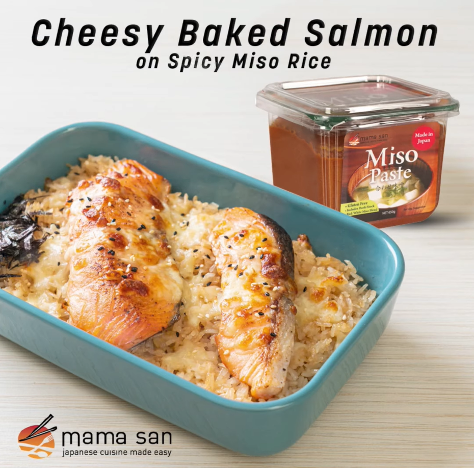 Cheesy baked salmon on spicy miso rice in a teal rectangular dish, next to a container of miso paste.