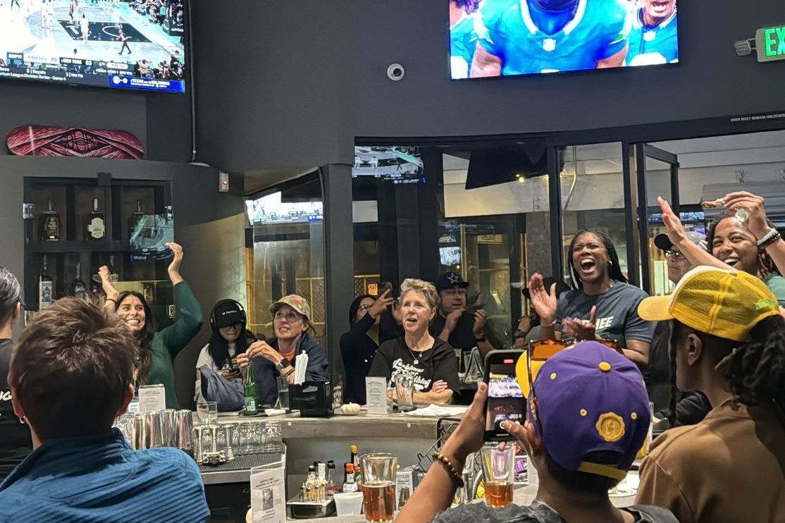 Women athletes kissing a trophy on a soccer field