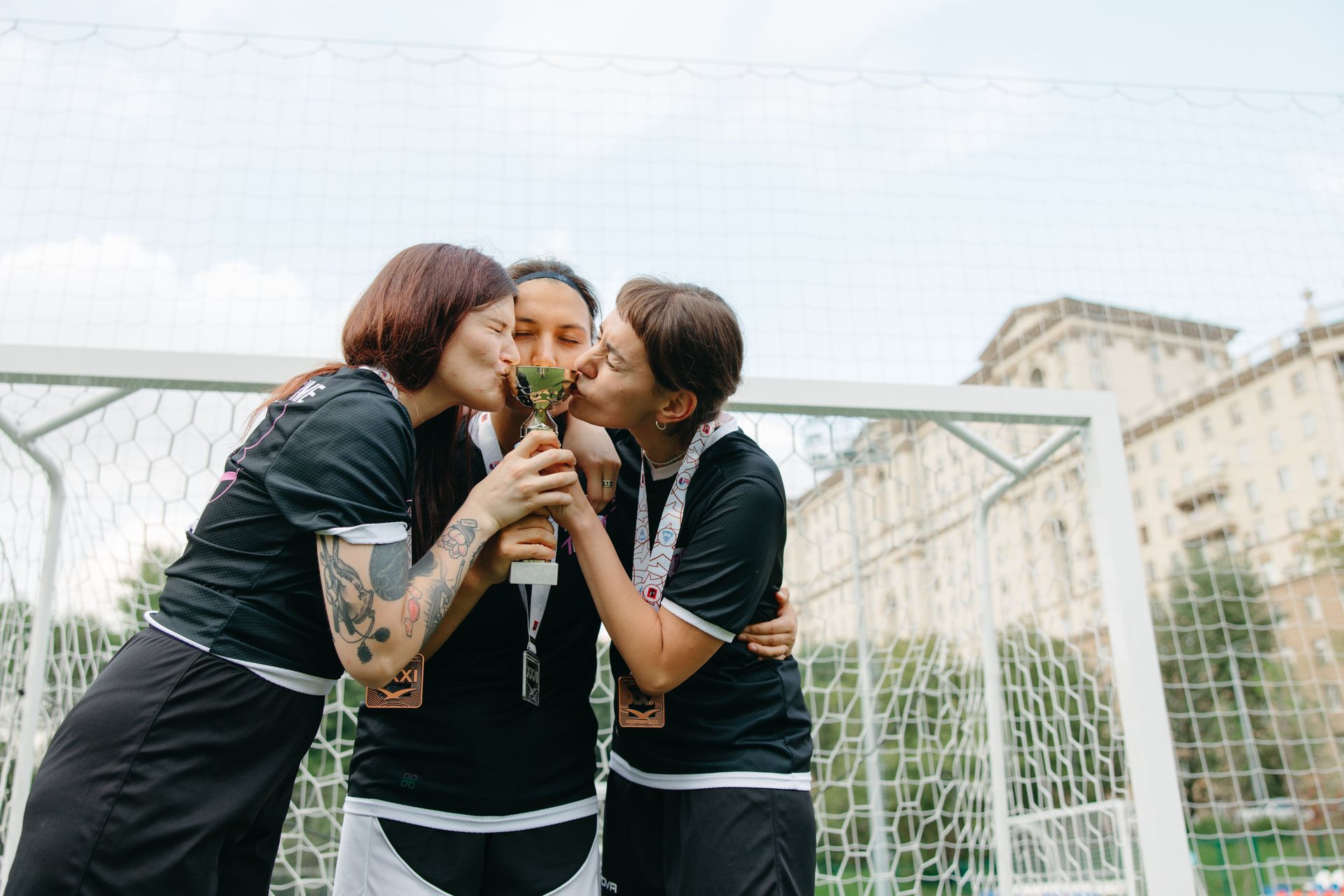 Women athletes kissing a trophy on a soccer field