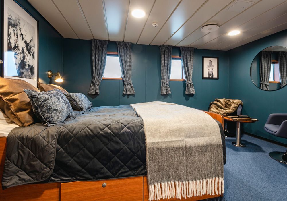 A bedroom with a bed , chair , table and mirror.