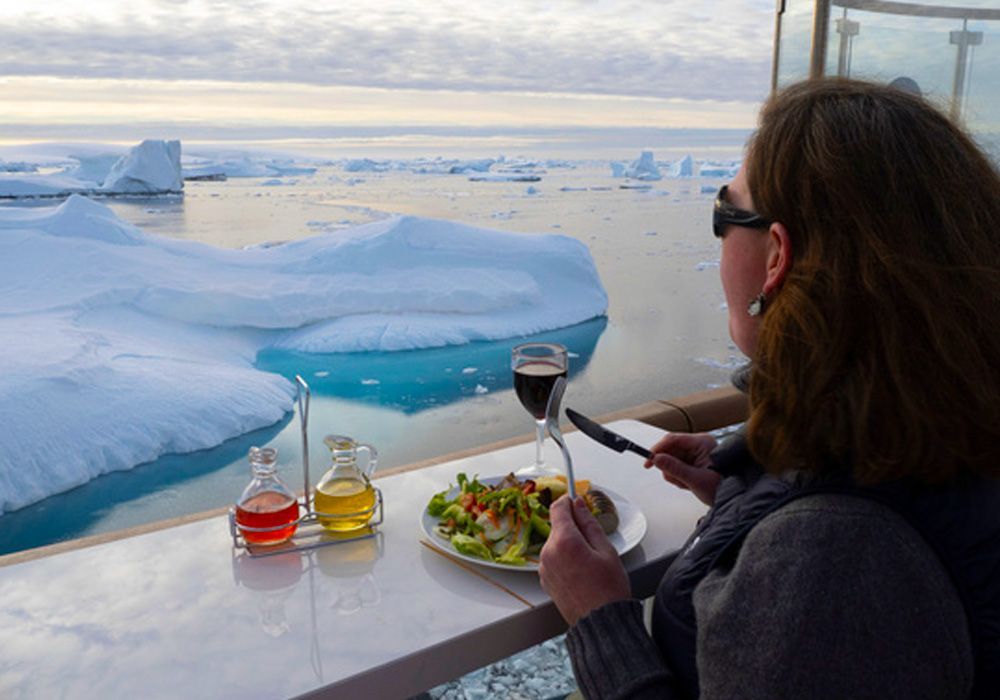 A woman is sitting at a table with a plate of food and a glass of wine.