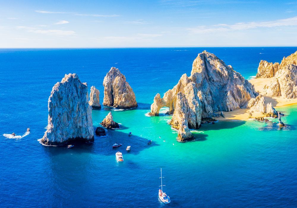 A group of boats are floating on top of a large body of water surrounded by rocks.