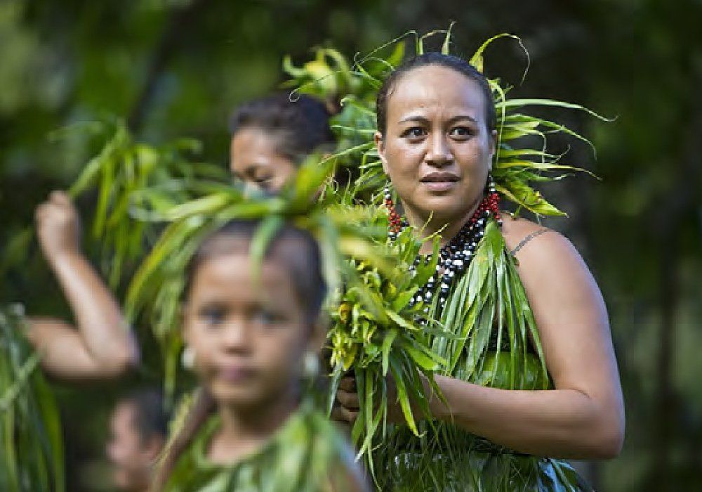 A woman in a green dress is holding a bunch of leaves in her hands.