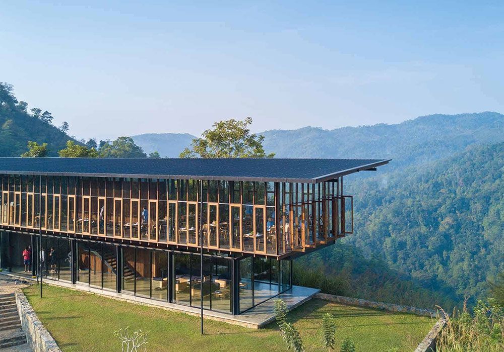 A large building is sitting on top of a hill in the middle of a forest.