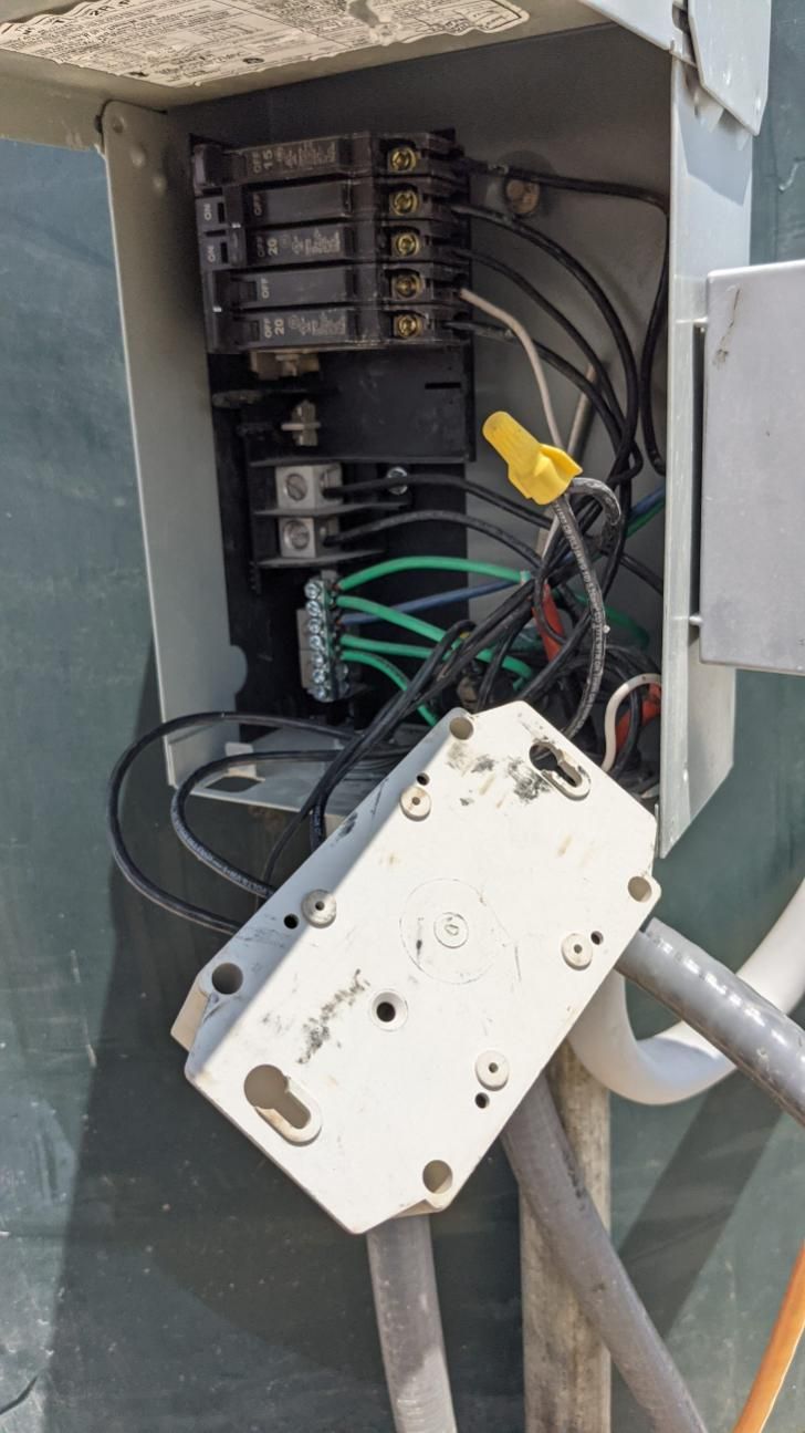 Open electrical sub-panel with various black, white, and green wires connected to breakers, terminals, and a junction box.