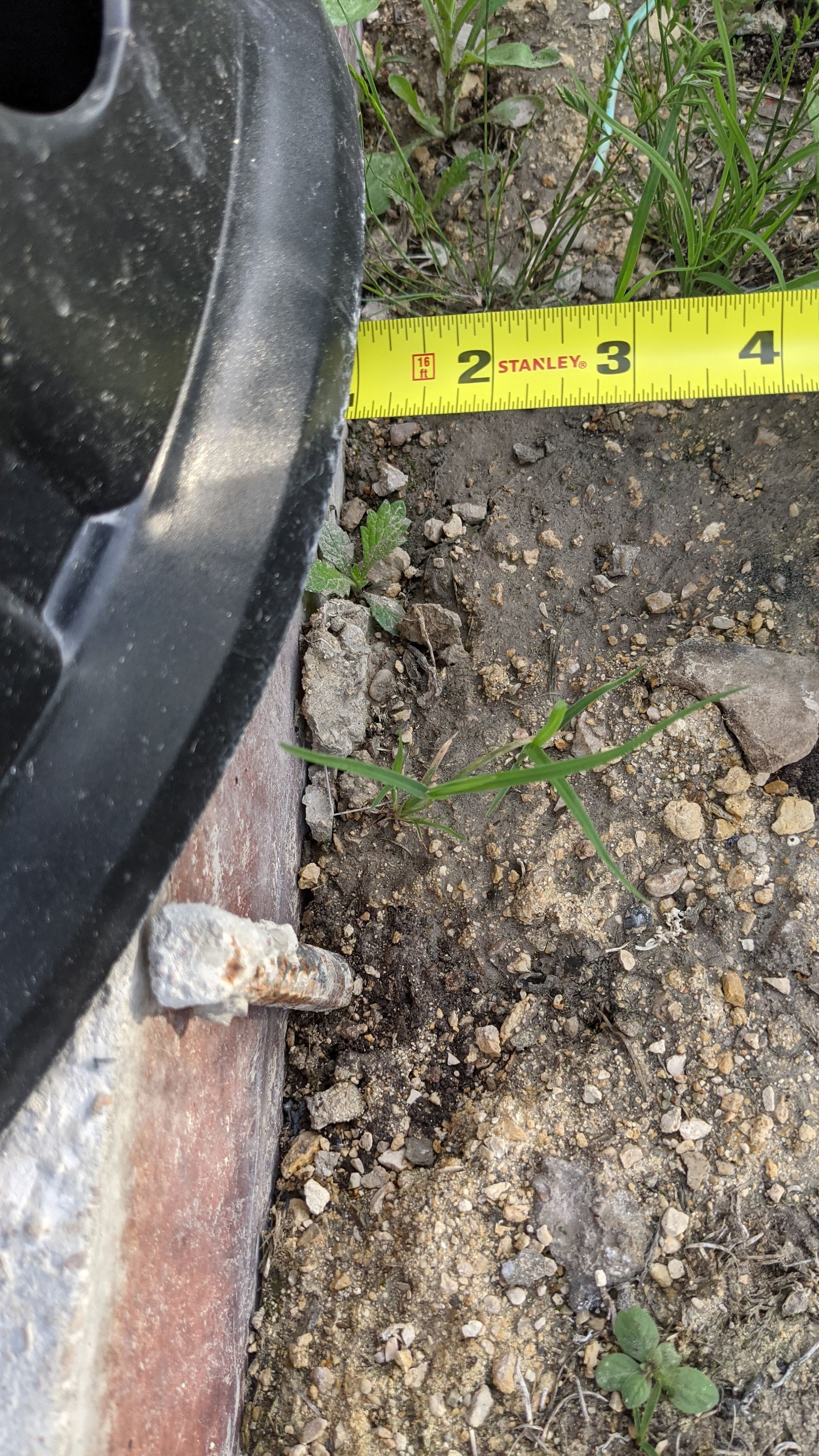 A yellow measuring tape shows a distance of approximately 1.5 inches from a black circular object to a small metal peg.