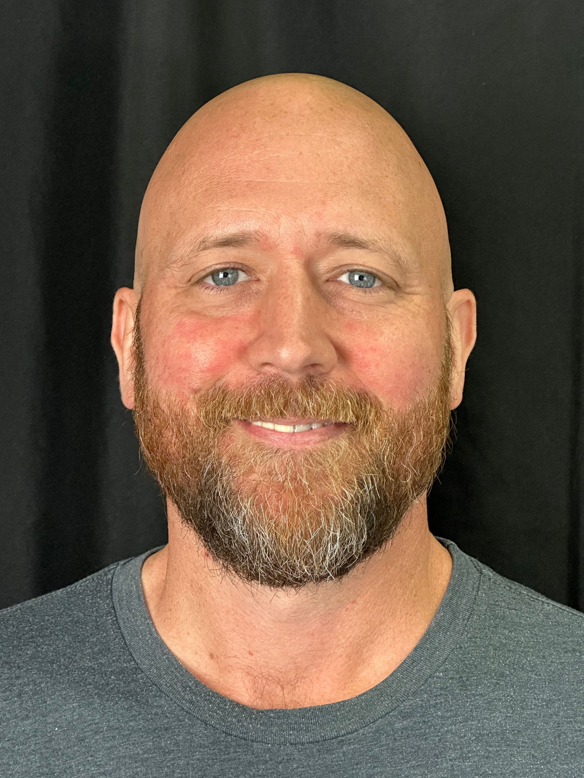 A man with glasses and a beard is smiling for the camera.