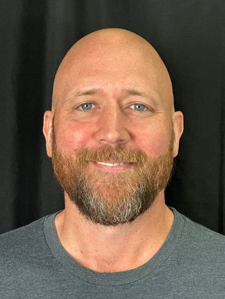 A man with glasses and a beard is smiling for the camera.