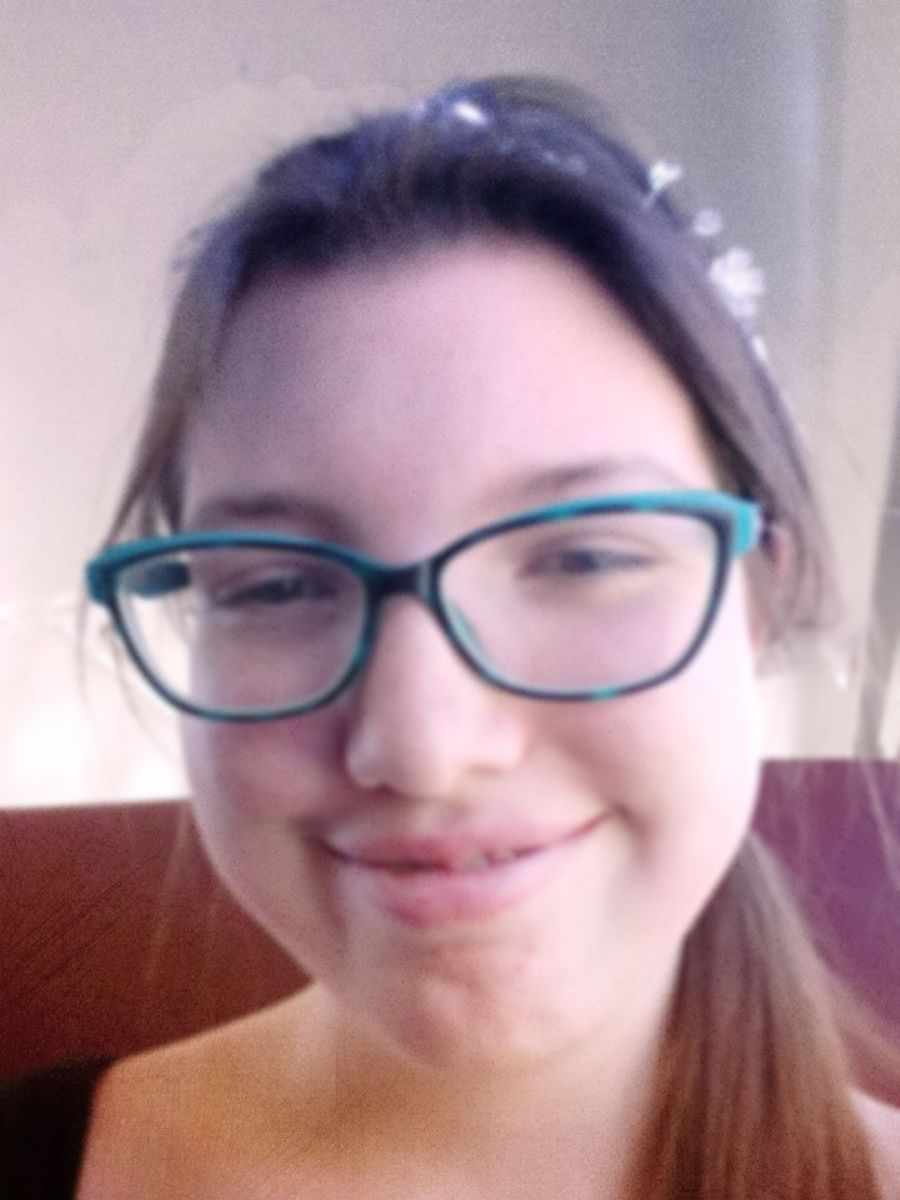 A girl wearing glasses and a ponytail smiles for the camera