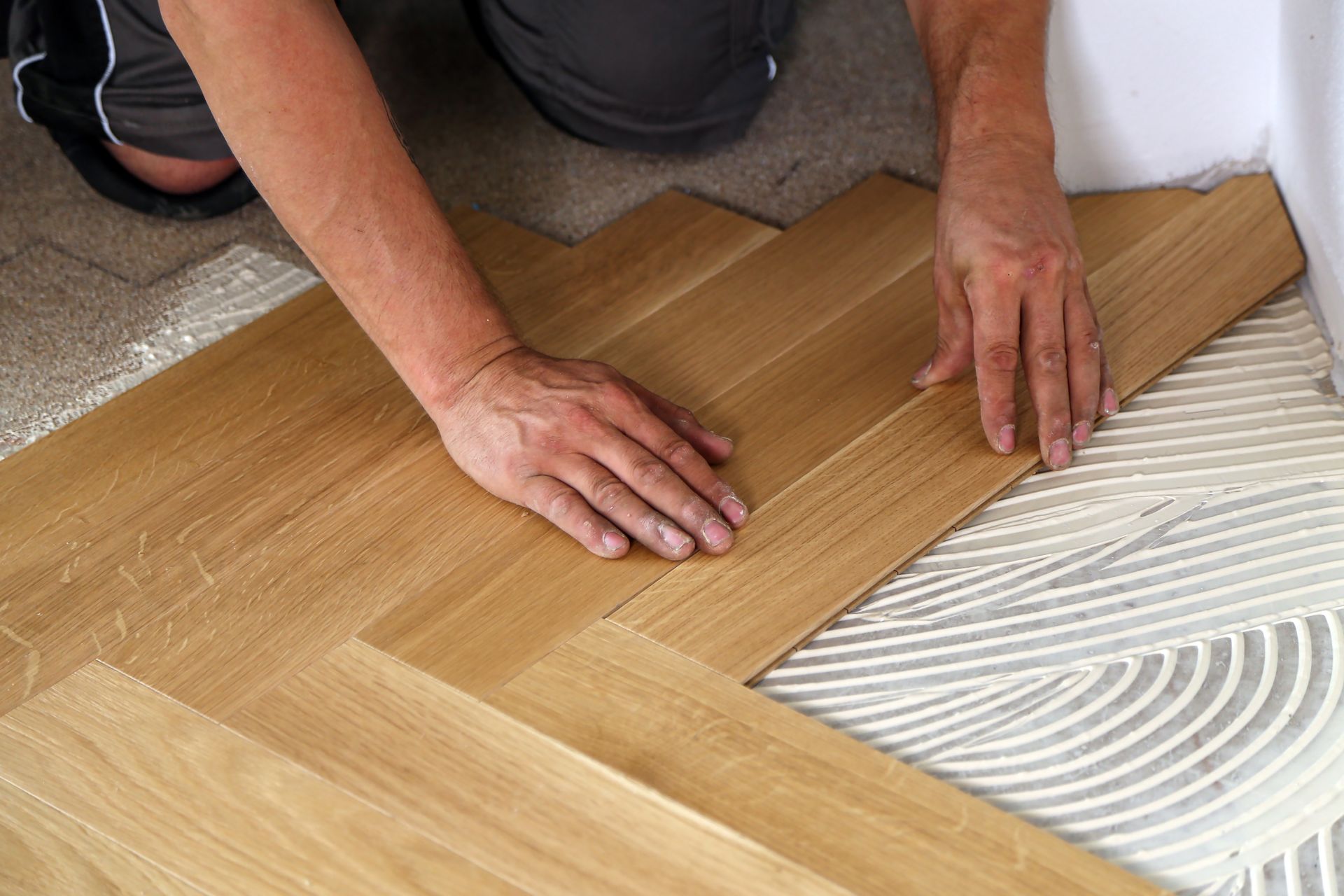 A man is laying a wooden floor on the floor.
