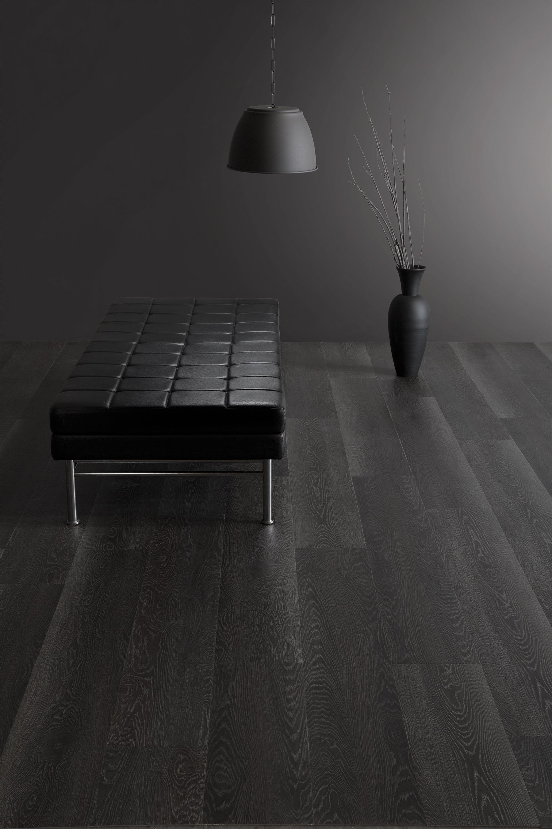 A black room with a black table and a vase on the floor.