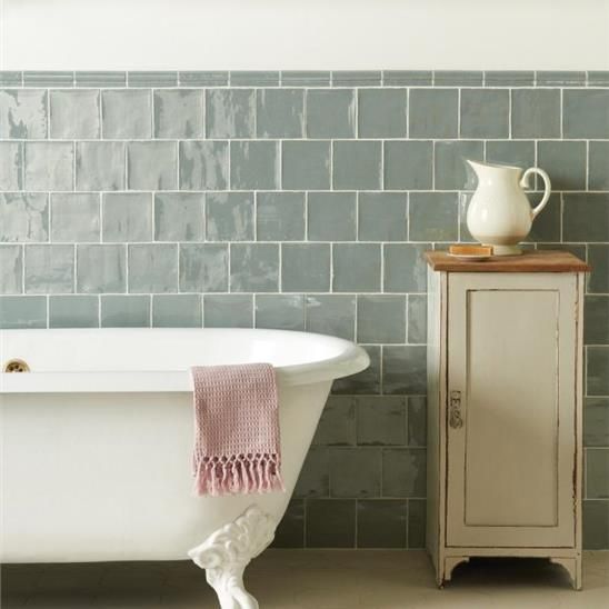 A bathroom with a bathtub and a cabinet with a pitcher on top of it