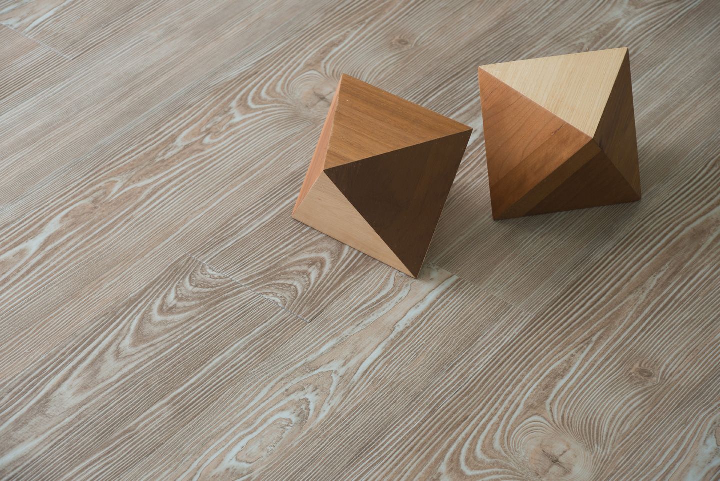 Two wooden pyramids are sitting on a wooden floor.