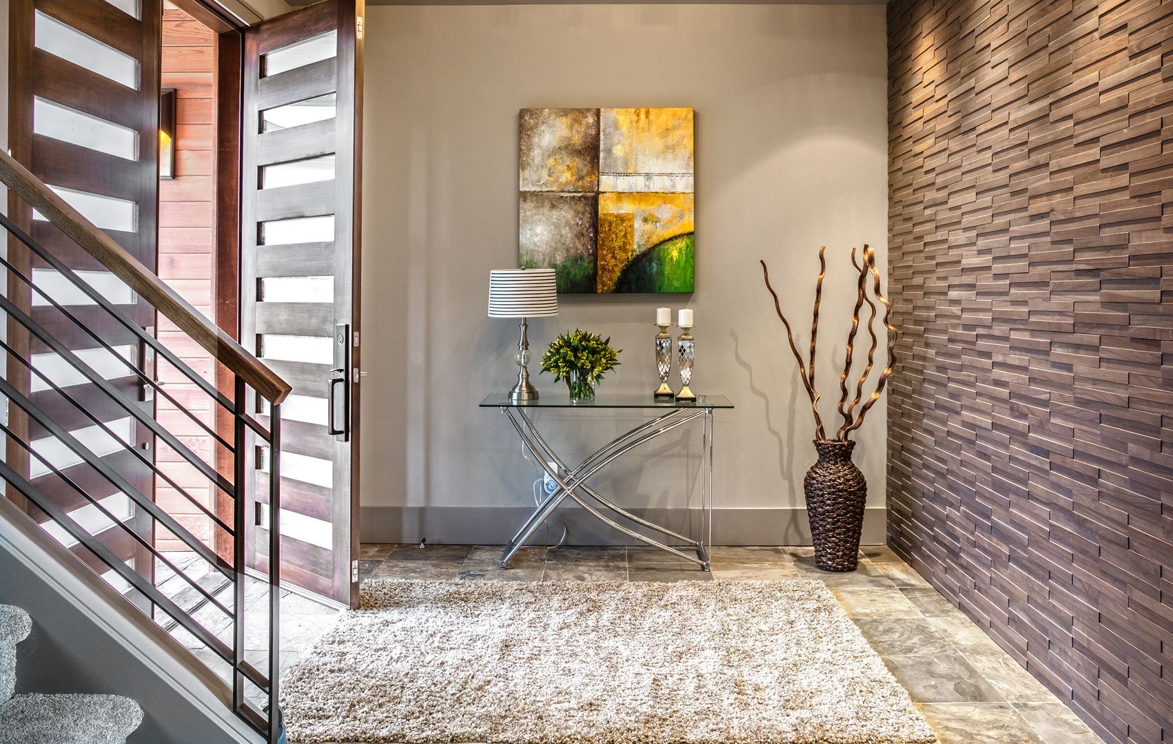 A hallway with stairs and a table with a vase of flowers on it.