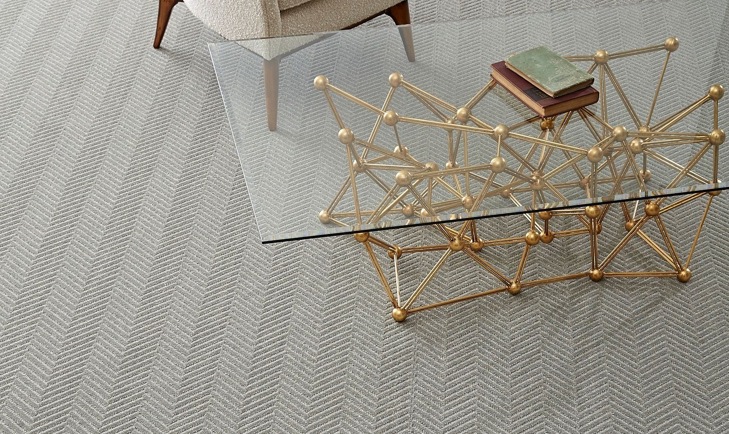 A living room with a glass coffee table and a chair.