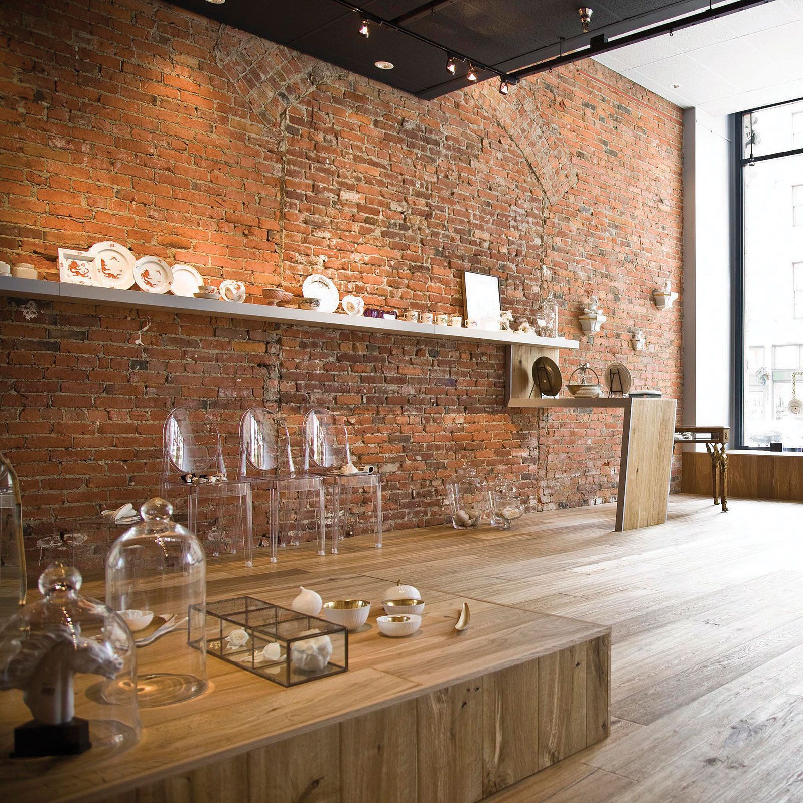 A room with a brick wall and glass jars on the floor