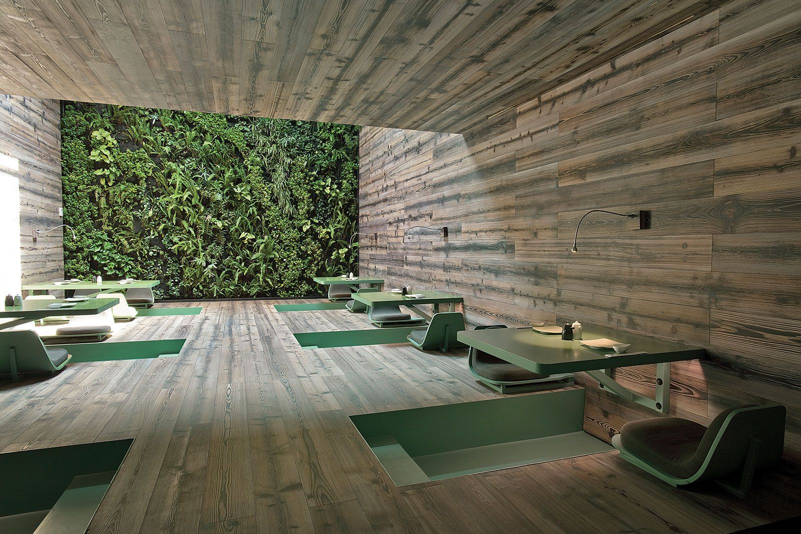 A room with tables and chairs and a green wall.