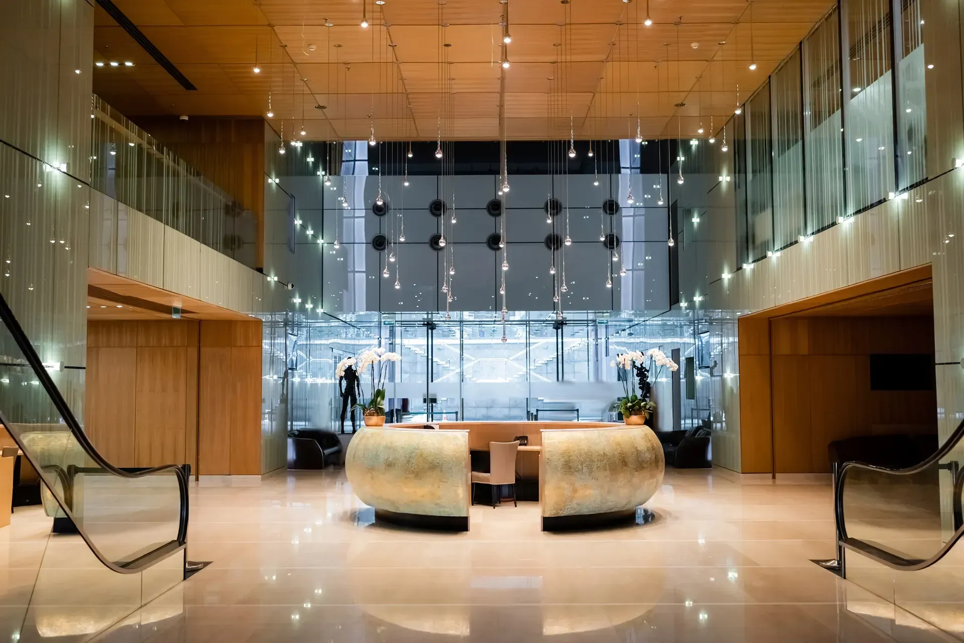 Elegant hotel lobby with reception desk, glass walls, and wood accents.