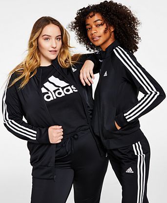 Two women are standing next to each other wearing black adidas clothes.