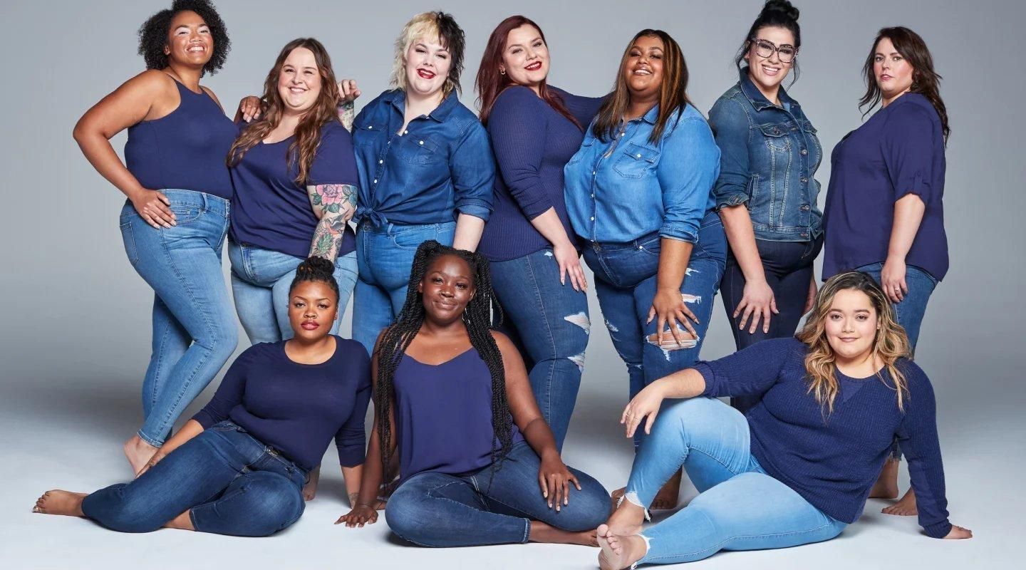 A group of plus size women are posing for a picture together all wearing denim.