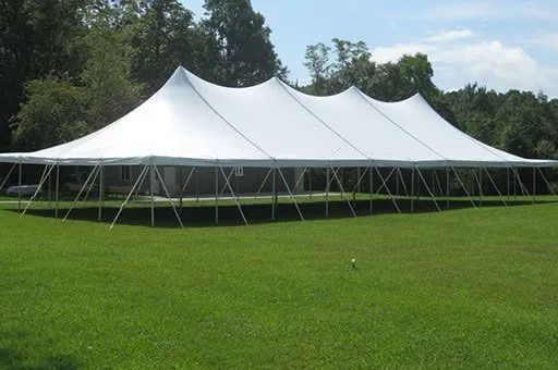 a large white tent is sitting in the middle of a grassy field.