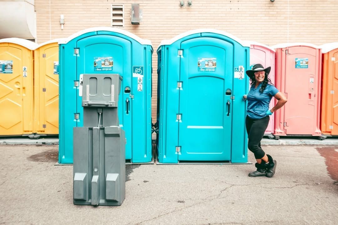 Blue portable toilets and a handwashing station at an outdoor event site.
