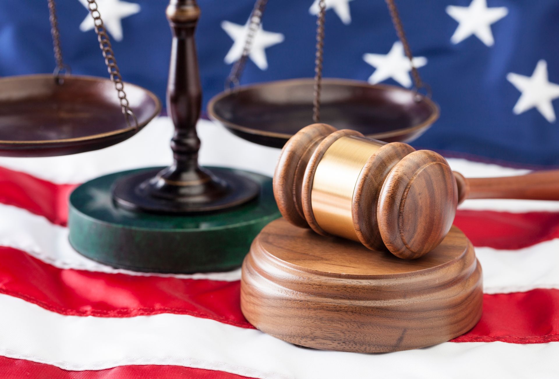 A wooden gavel and justice balance on the American flag. A wooden gavel and justice balance on the American flag.