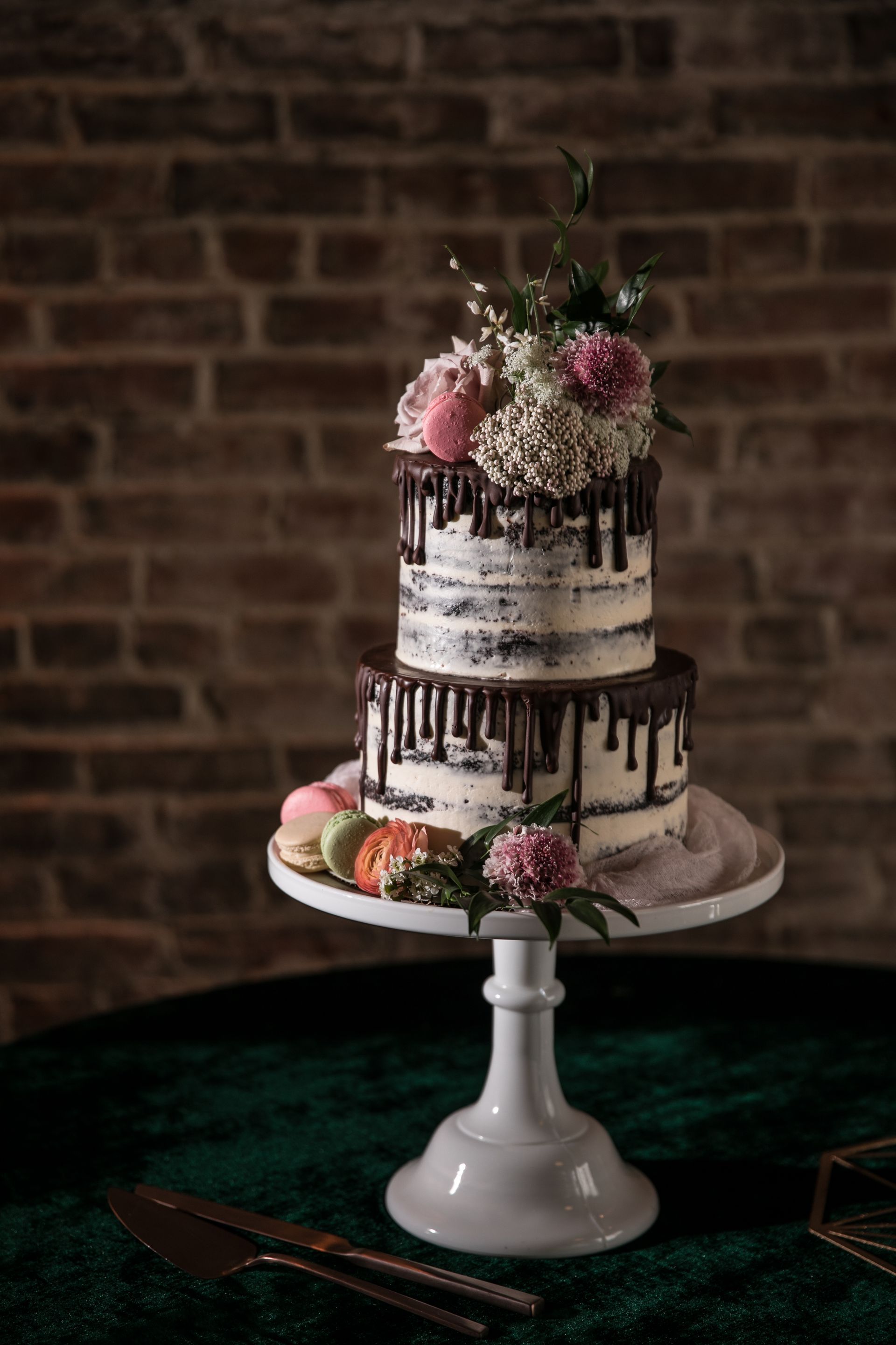 A wedding cake is sitting on top of a white cake stand on a table.