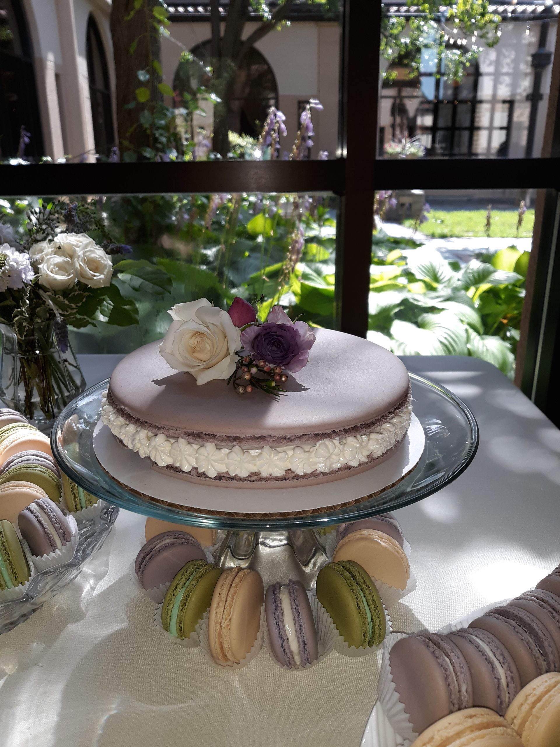 A cake on a glass plate with macarons around it