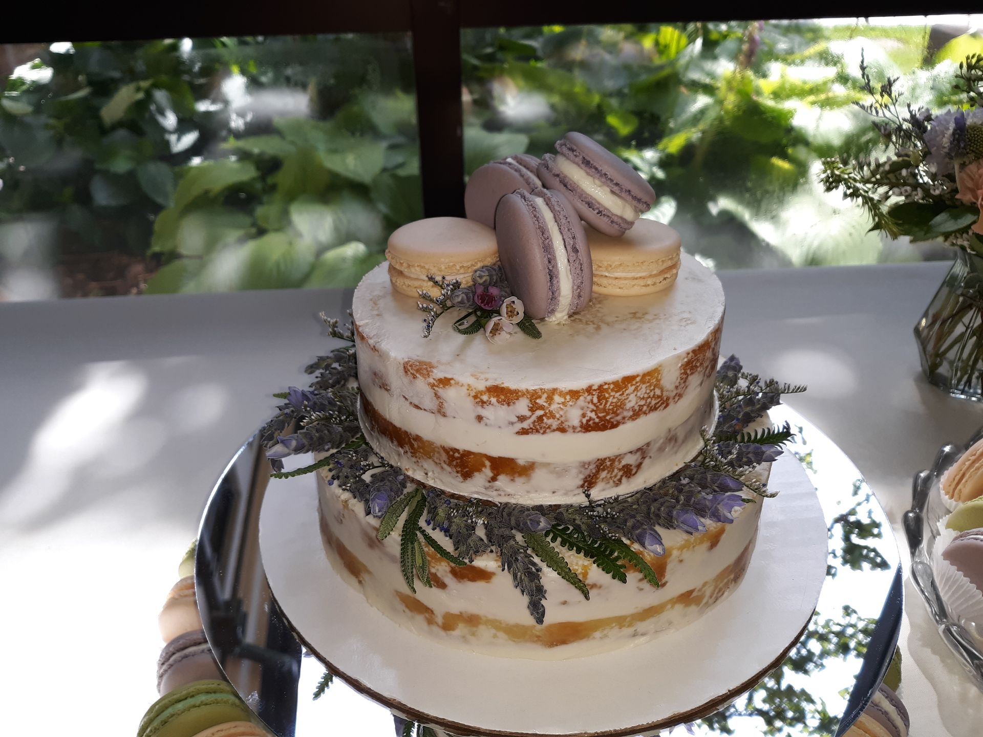 A wedding cake topped with colorful macarons and delicate lavender sprigs