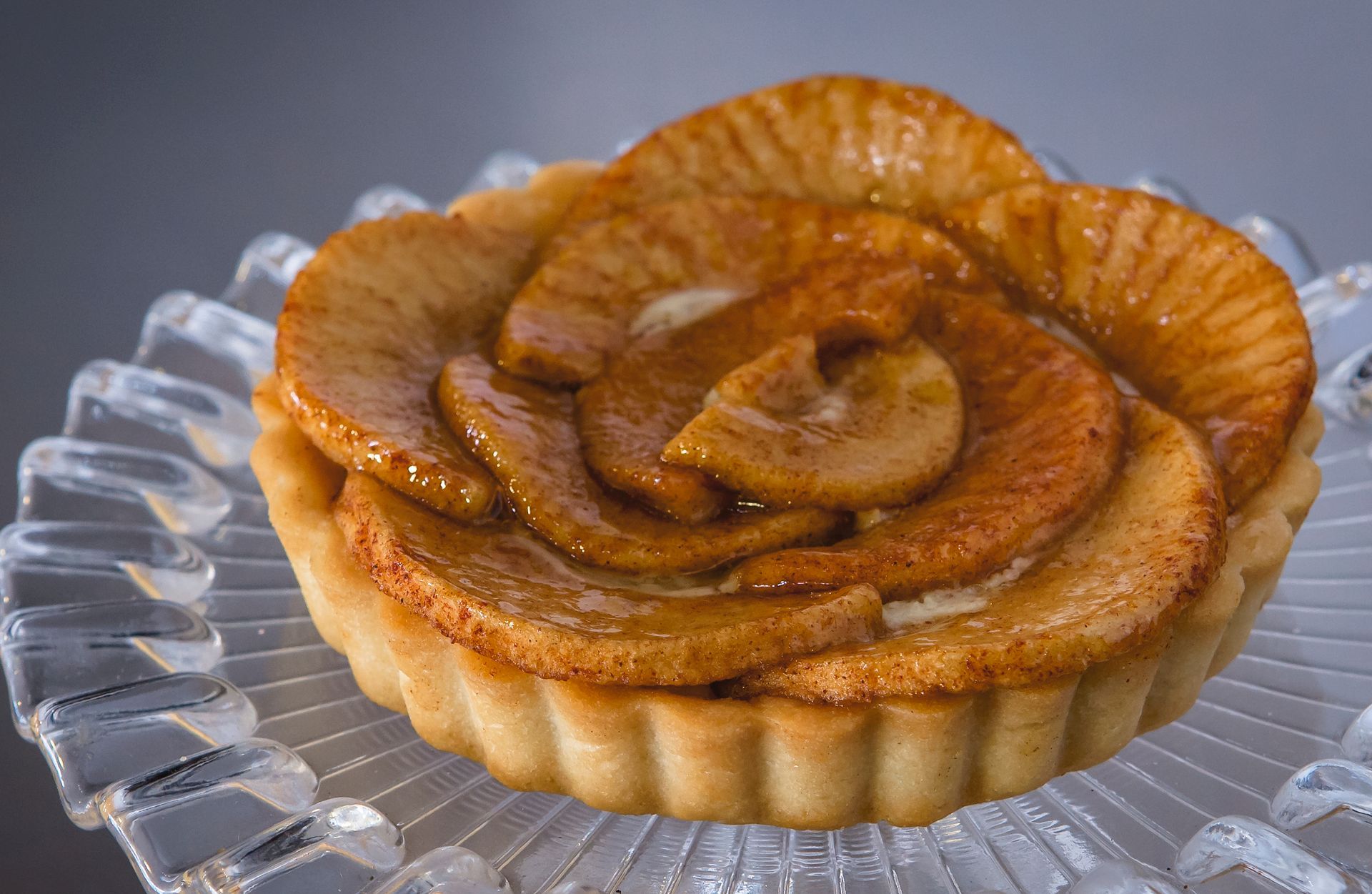 A small apple pie is sitting on a glass plate.