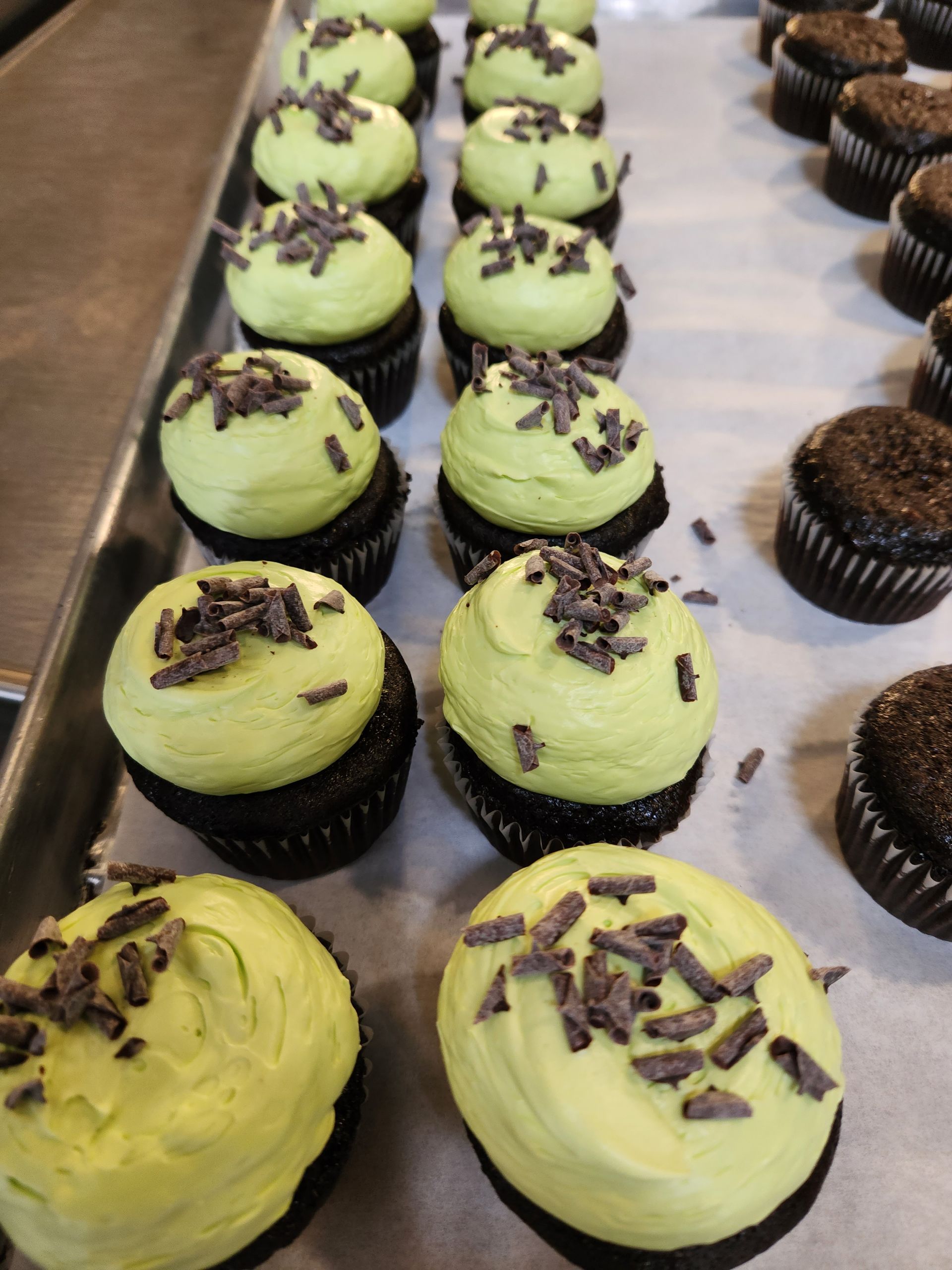 A tray of cupcakes with green frosting and chocolate sprinkles