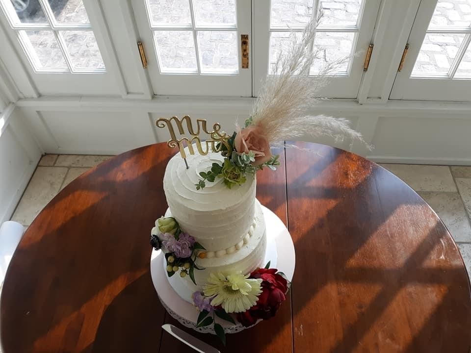 A wedding cake is sitting on top of a wooden table.