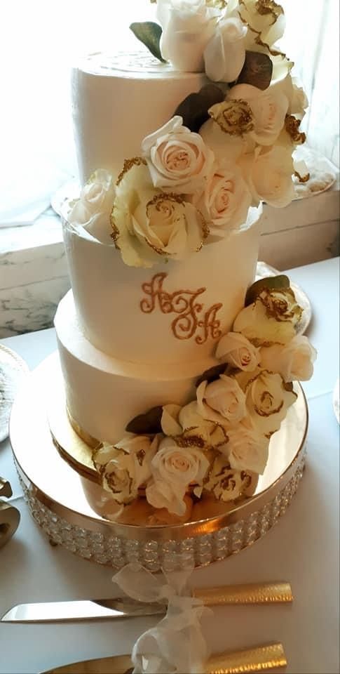 A three tiered wedding cake with white roses on top of it.