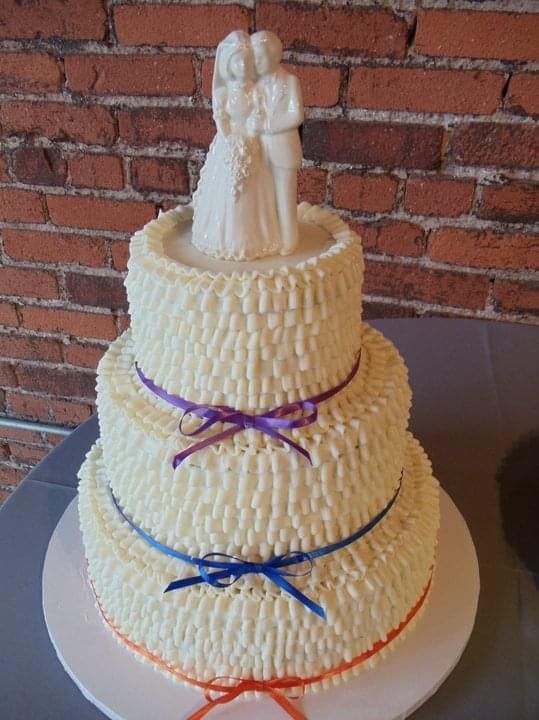 A wedding cake with a bride and groom figurine on top