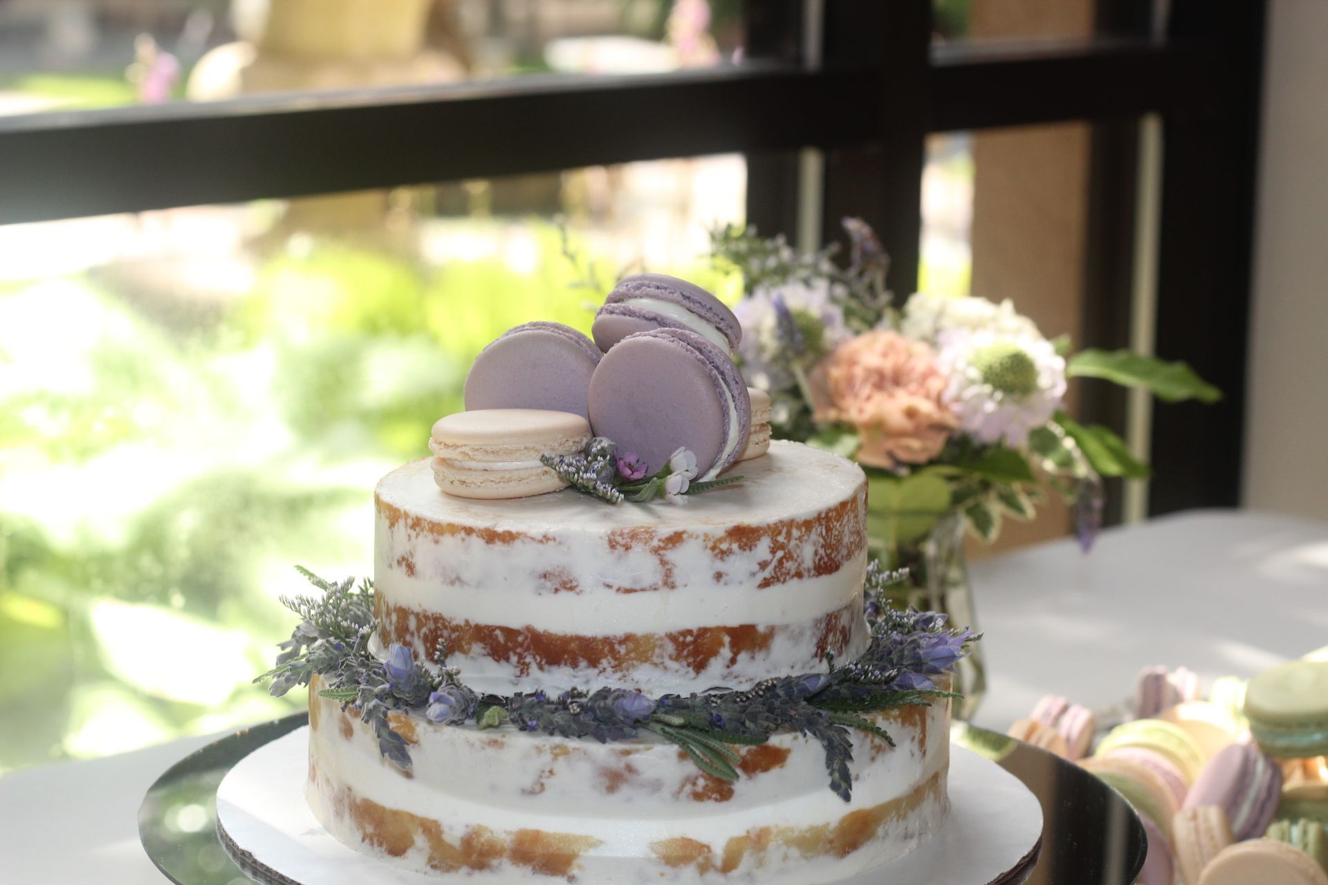 A wedding cake topped with colorful macarons and delicate lavender sprigs
