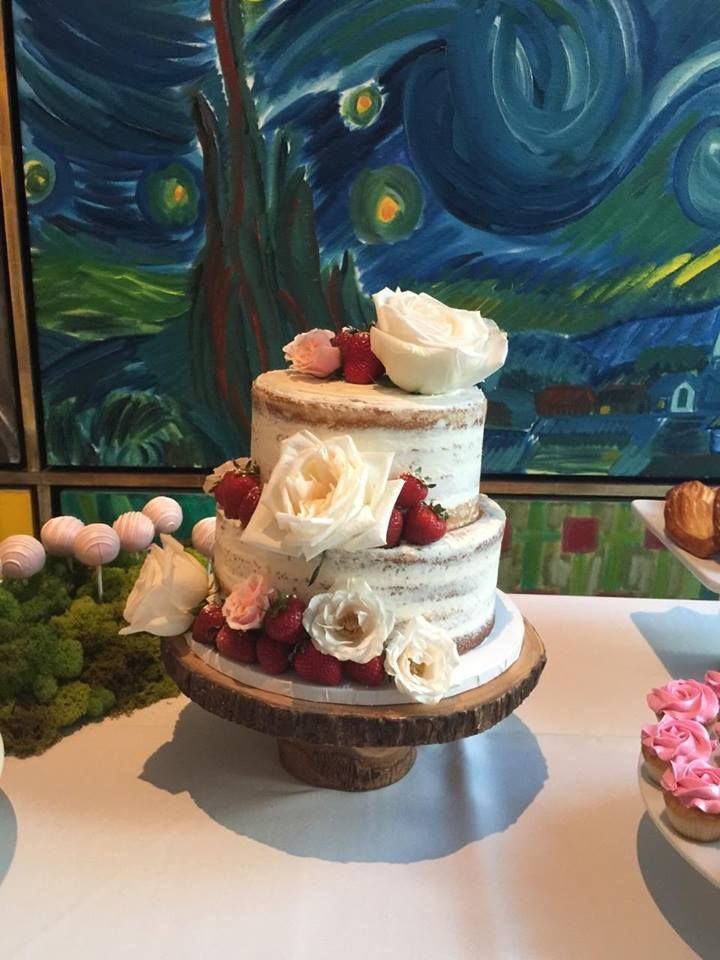 A beautifully decorated wedding cake surrounded by an assortment of cupcakes and various desserts on a table