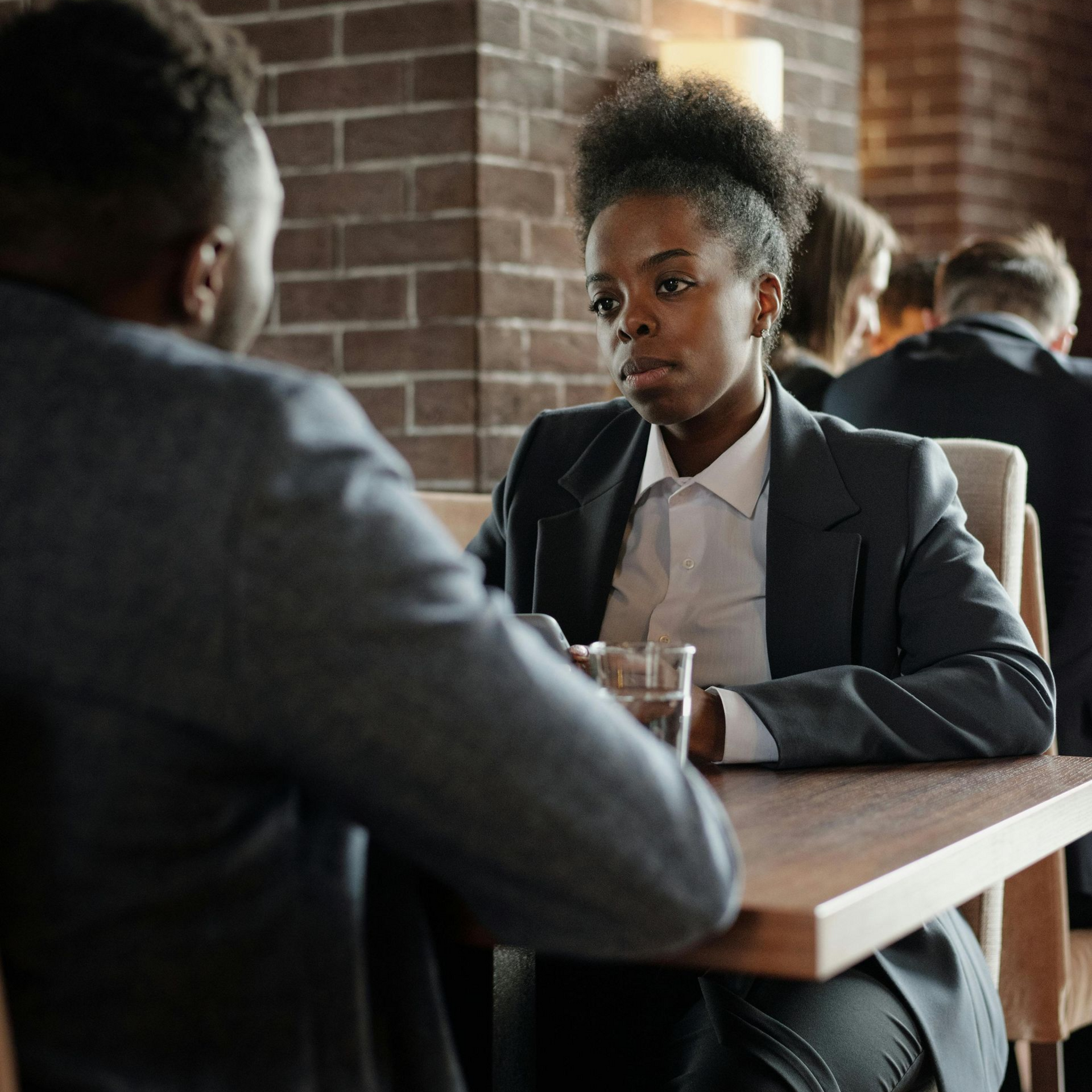Two people shaking hands over a desk in an office setting.
