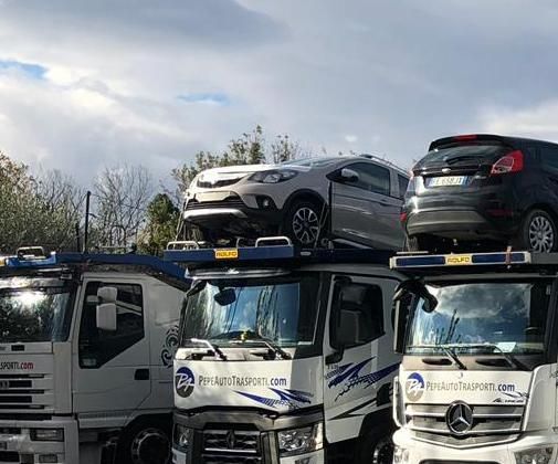Un gruppo di carri attrezzi con delle auto sopra.
