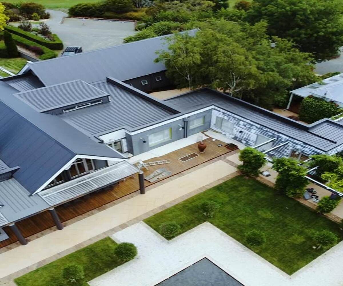 An Aerial View of the roof of a Large House Surrounded By Trees and Grass in Wollongong