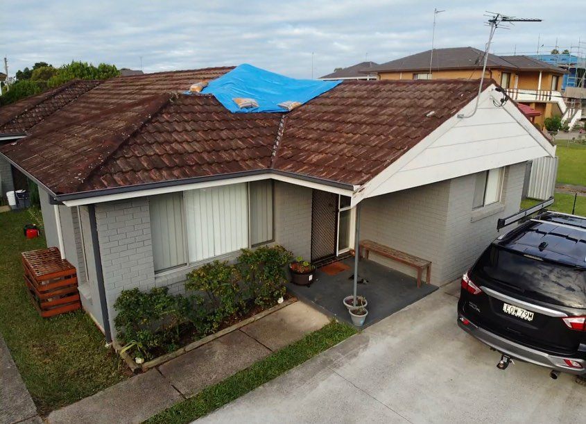 An Aerial View Of A House With A Blue Tarp On The Roof — Elevated Roofing Systems Pty Ltd In Barrack Heights, NSW